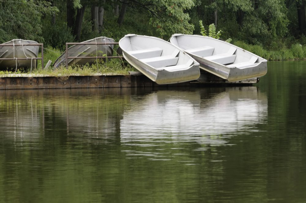 Boats of summer above water Pair of white rowboats on dock above reflecting lake